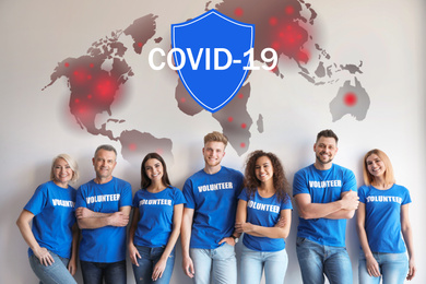 Image of Volunteers uniting to help during COVID-19 outbreak. Group of people on light background, world map and shield illustrations