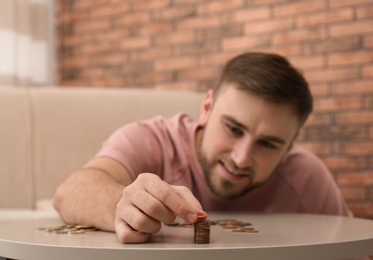 Young man with coins at home, closeup. Saving money