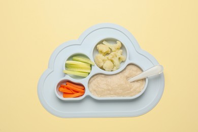 Photo of Healthy baby food in plate on yellow background, top view