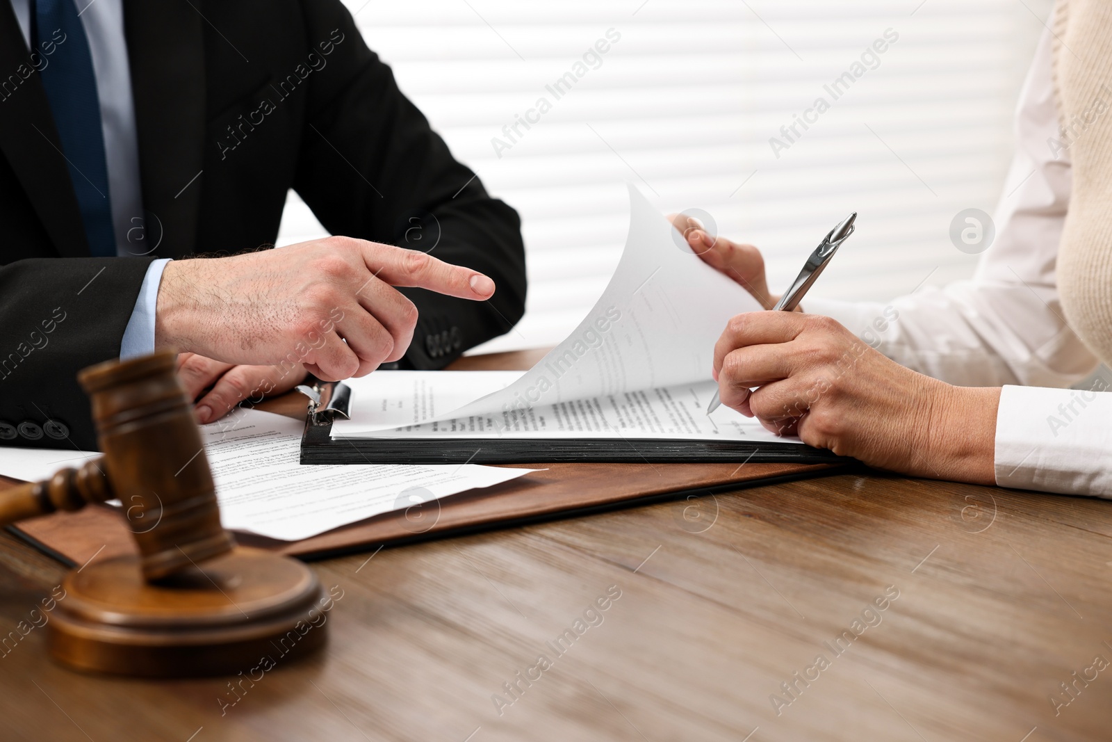 Photo of Senior woman signing document in lawyer's office, closeup