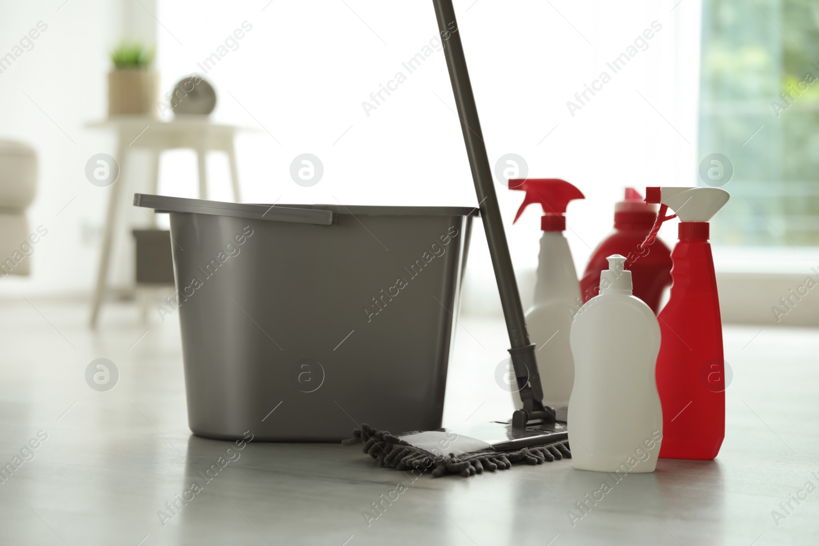 Photo of Bucket, different cleaning supplies and mop on floor indoors