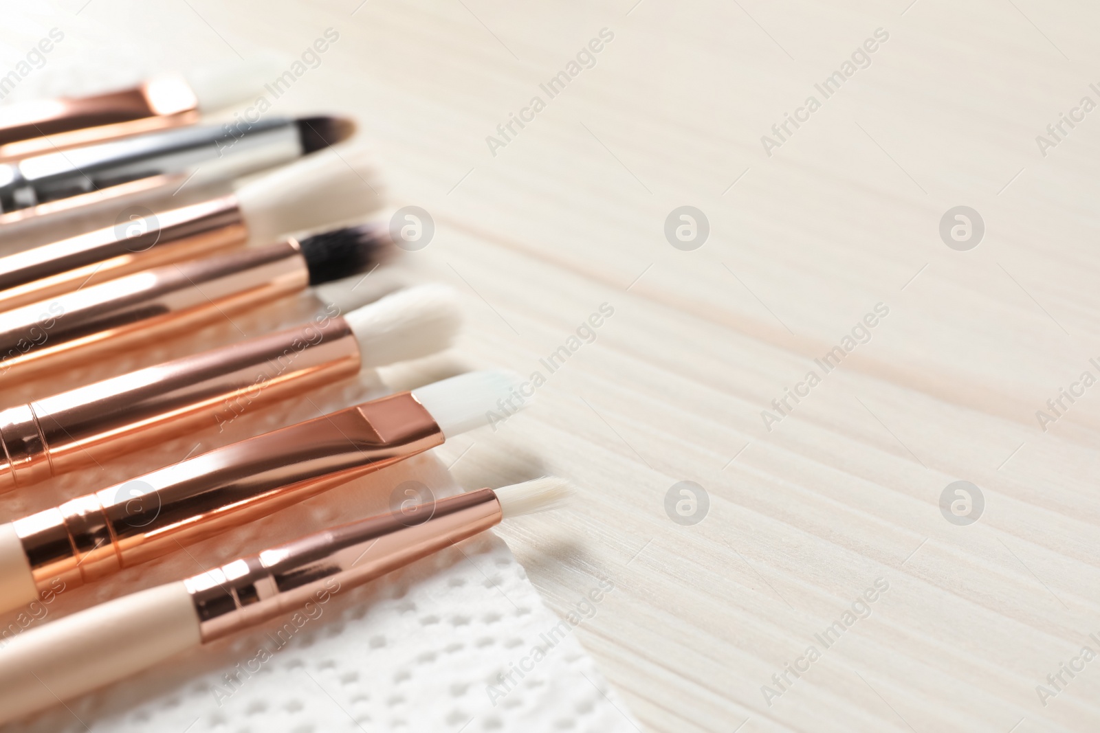 Photo of Set of different makeup brushes drying after cleaning on white wooden table, closeup. Space for text