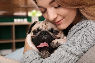 Woman with cute pug dog at home, closeup. Animal adoption