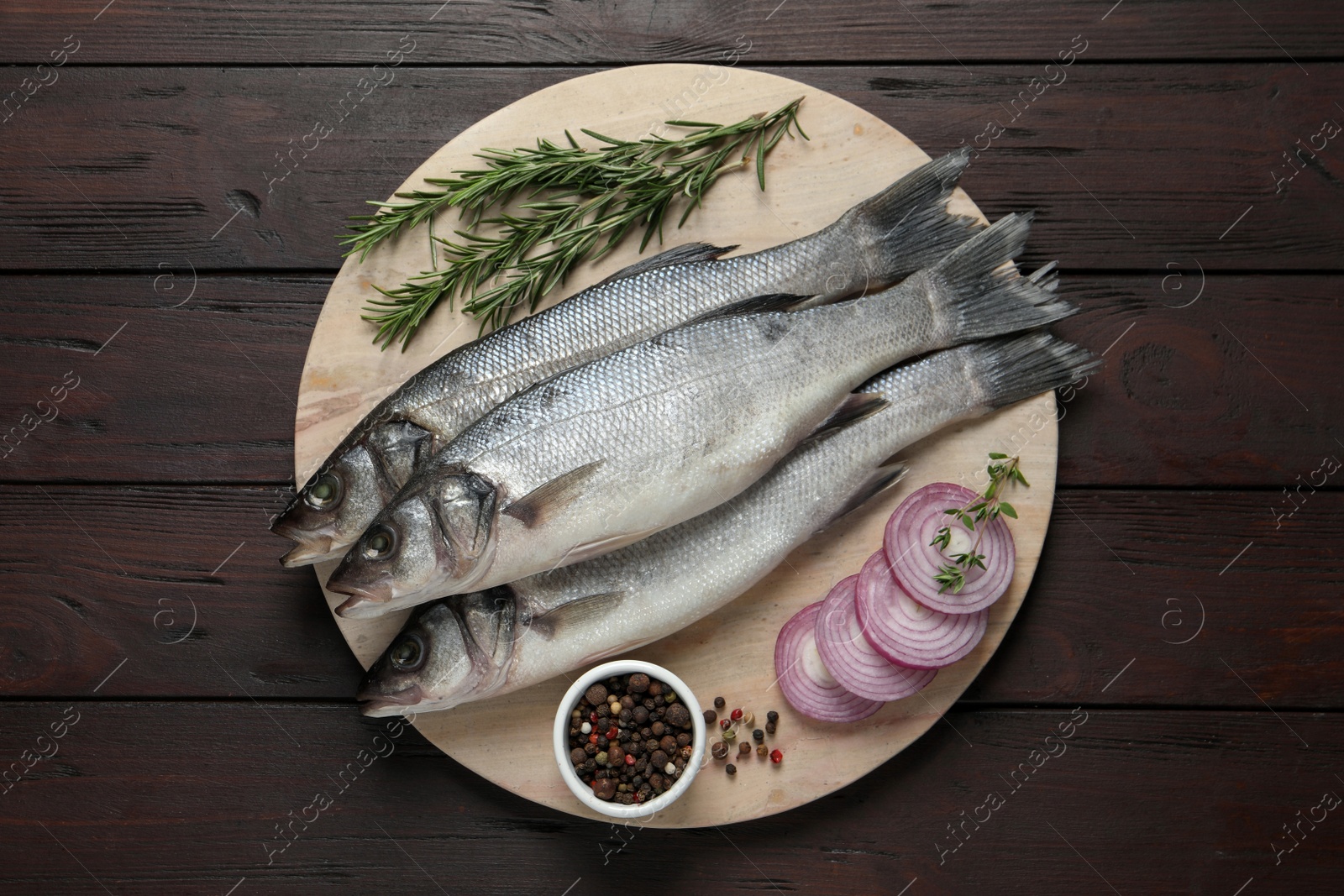 Photo of Sea bass fish and ingredients on wooden table, top view