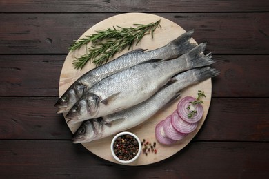 Photo of Sea bass fish and ingredients on wooden table, top view