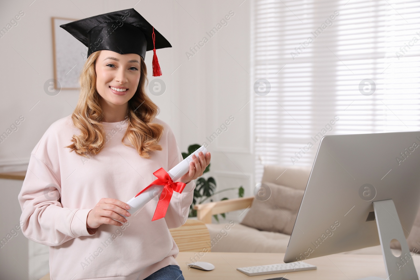 Photo of Happy student with graduation hat and diploma at workplace in office