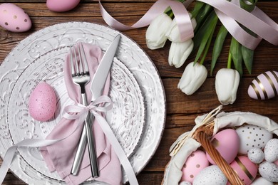 Festive table setting with painted eggs and tulips, flat lay. Easter celebration