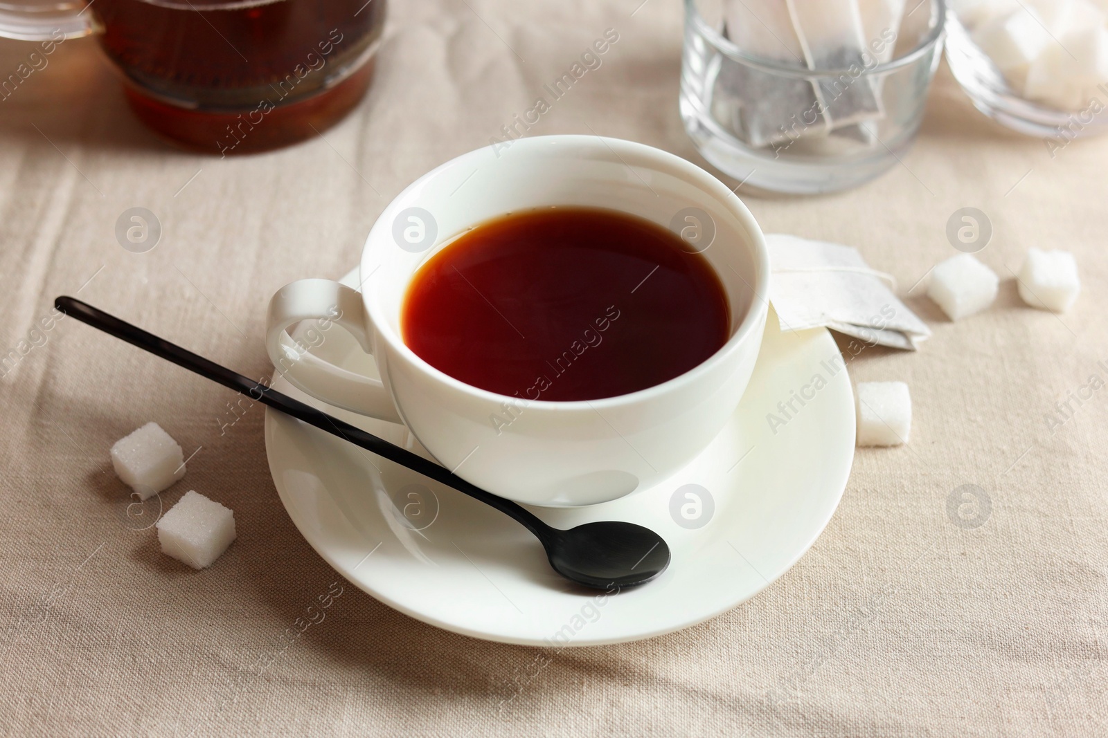 Photo of Tasty tea in cup and sugar cubes on light table