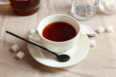 Tasty tea in cup and sugar cubes on light table