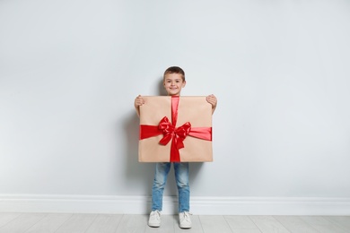 Image of Cute little boy dressed as gift box near white wall. Christmas suit