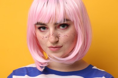 Beautiful woman with bright makeup and glitter freckles on yellow background