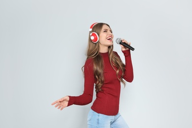 Young woman singing into microphone on color background. Christmas music