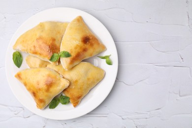 Delicious samosas and basil on white textured table, top view. Space for text