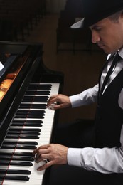 Photo of Man playing grand piano indoors. Talented musician