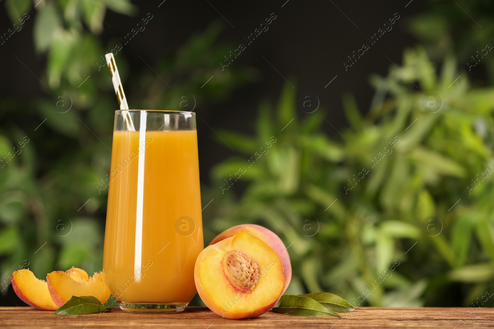 Photo of Natural peach juice and fresh fruits on wooden table. Space for text