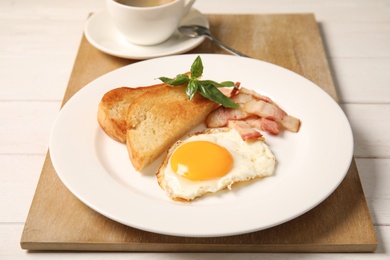 Photo of Fried egg with bacon and toasted bread on plate served for breakfast