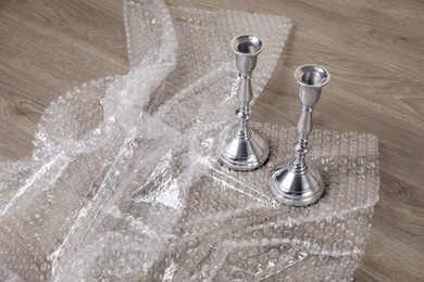 Photo of Candlesticks with bubble wrap on wooden table