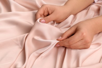 Photo of Woman touching delicate beige fabric, closeup view