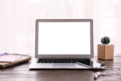 Modern computer with blank screen on wooden table at workplace. Space for design