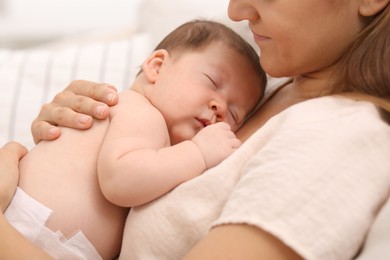 Mother holding her cute newborn baby indoors