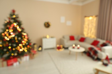 Blurred view of beautiful Christmas tree decorated with baubles in room with cozy furniture. Interior design