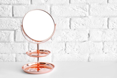 Photo of Modern mirror on table near brick wall