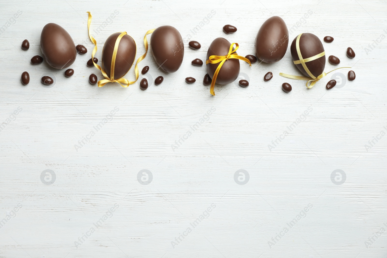 Photo of Flat lay composition with chocolate Easter eggs on wooden background, space for text