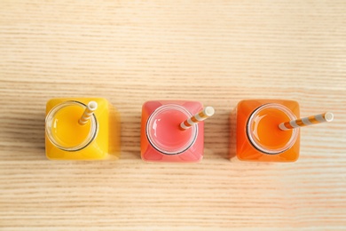 Photo of Bottles with tasty juices on wooden background, top view