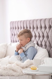 Photo of Sick little boy with cough suffering from cold in bed