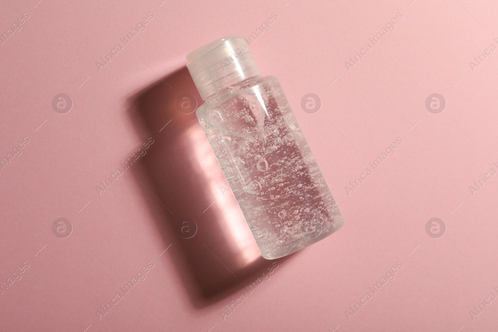 Photo of Bottle of cosmetic gel on pink background, top view