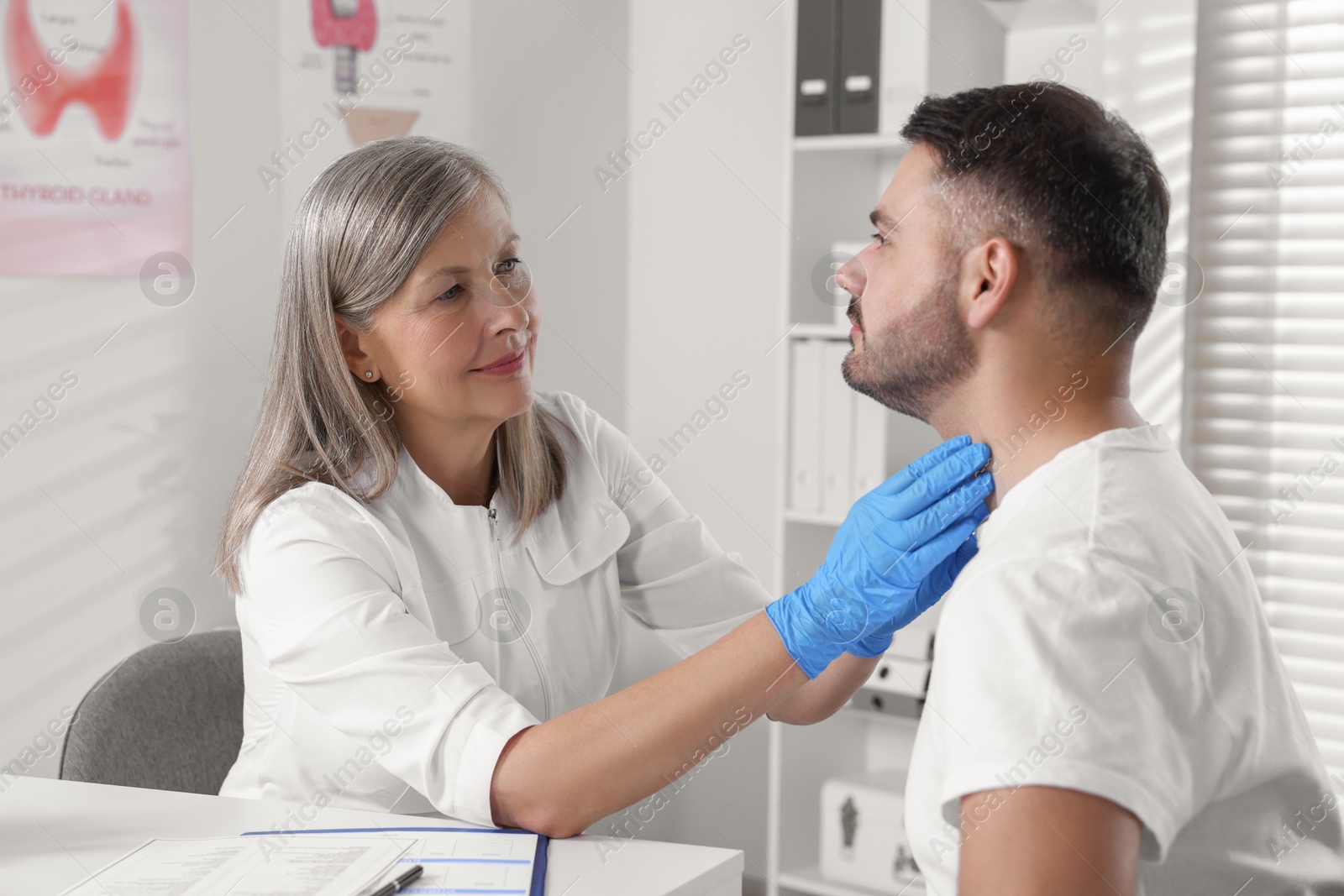 Photo of Endocrinologist examining thyroid gland of patient at table in hospital