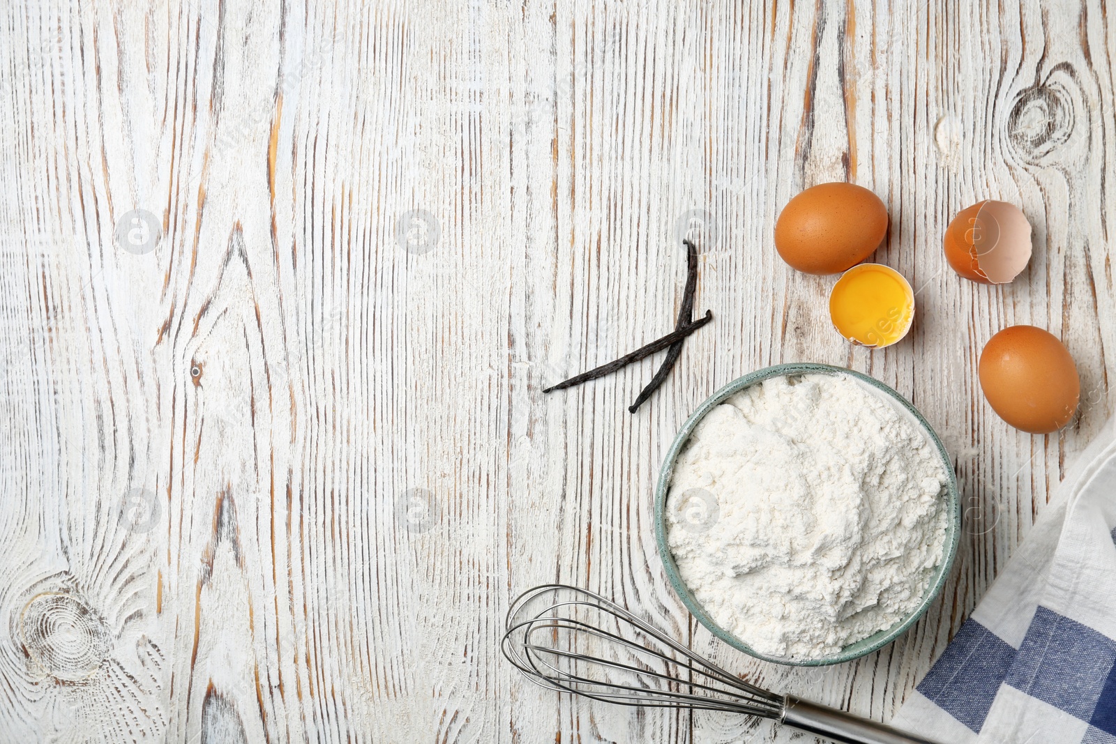 Photo of Bowl with flour, eggs and whisk on wooden background, top view