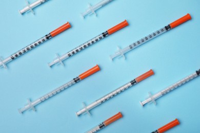 Disposable syringes on light blue background, flat lay