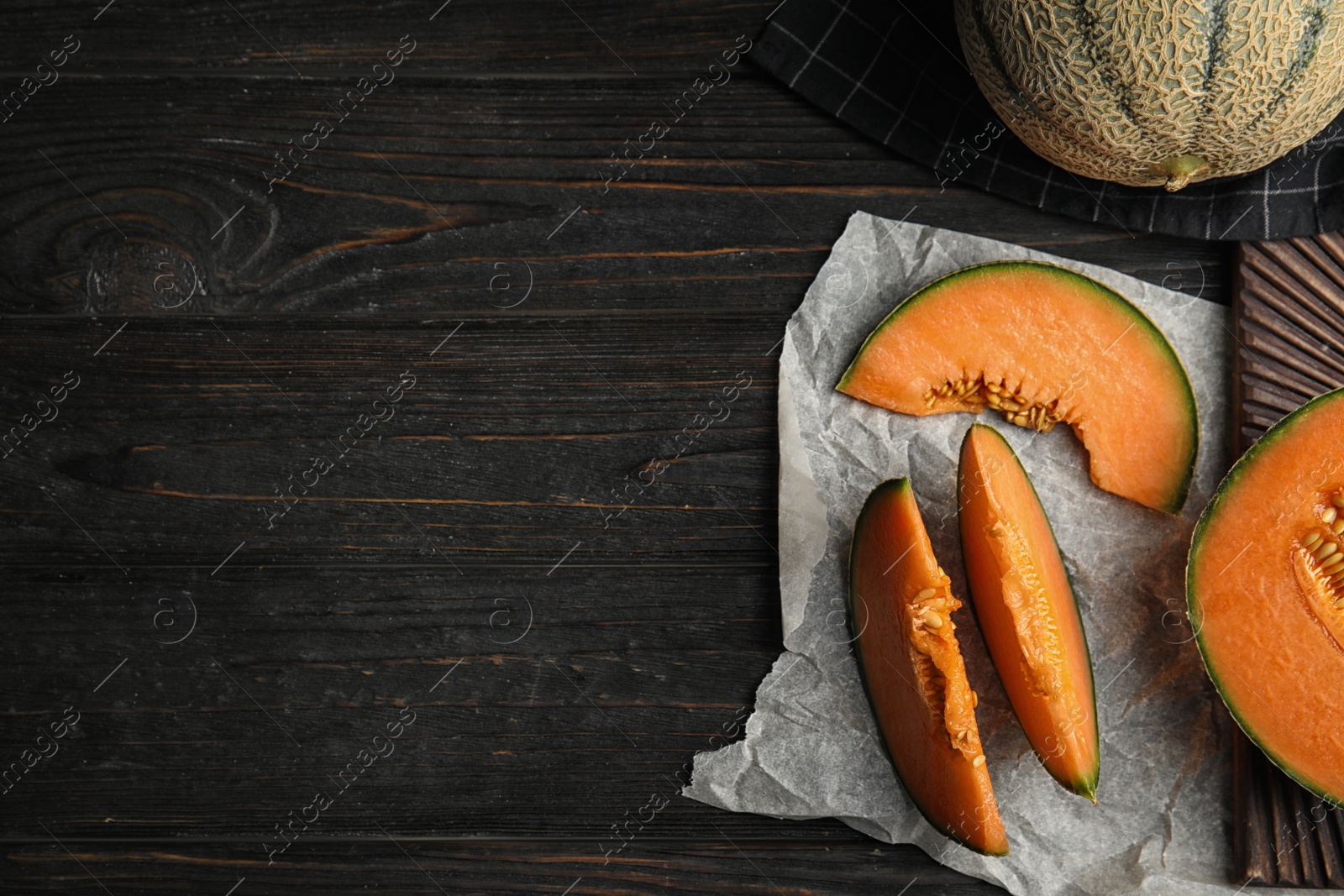 Photo of Flat lay composition with ripe cantaloupe melon on black wooden table. Space for text