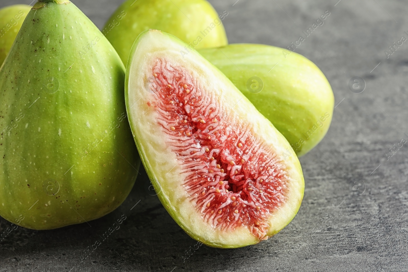 Photo of Fresh ripe figs on gray background, closeup. Tropical fruit