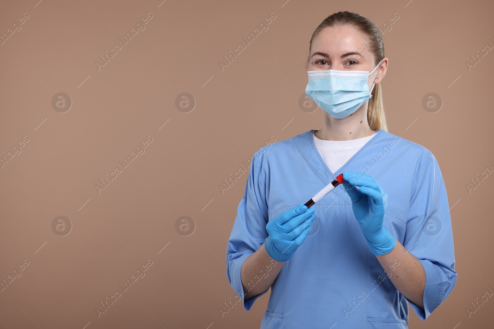 Photo of Laboratory testing. Doctor with blood sample in tube on light brown background, space for text
