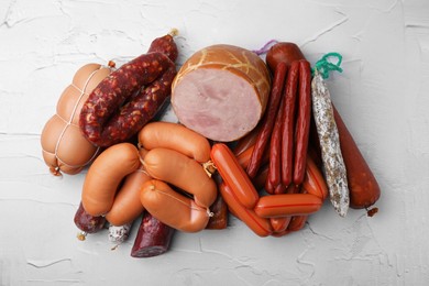 Photo of Different types of sausages on white textured table, flat lay