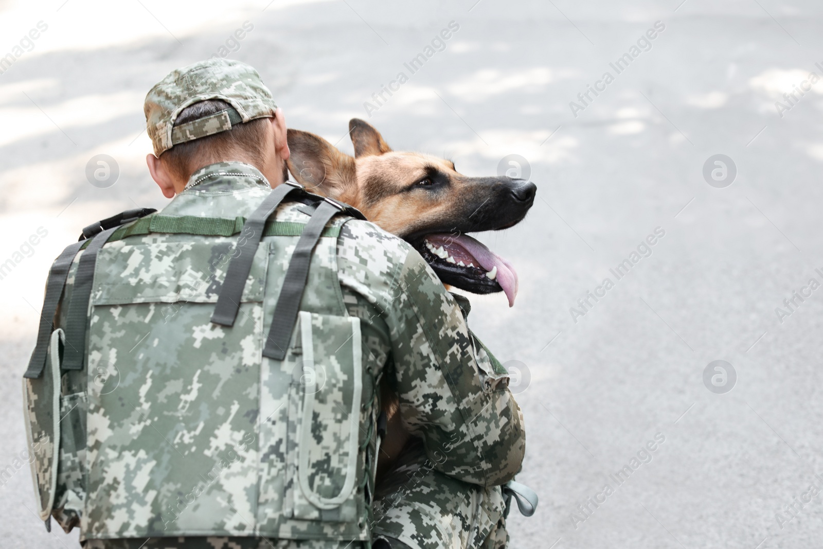 Photo of Man in military uniform with German shepherd dog outdoors