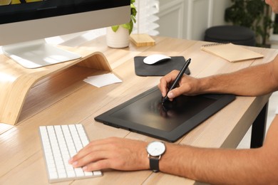 Professional retoucher working on graphic tablet at desk, closeup