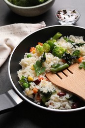 Tasty fried rice with vegetables served on black table, closeup