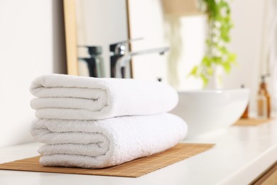 Photo of Stacked soft towels on white table in bathroom. Space for text