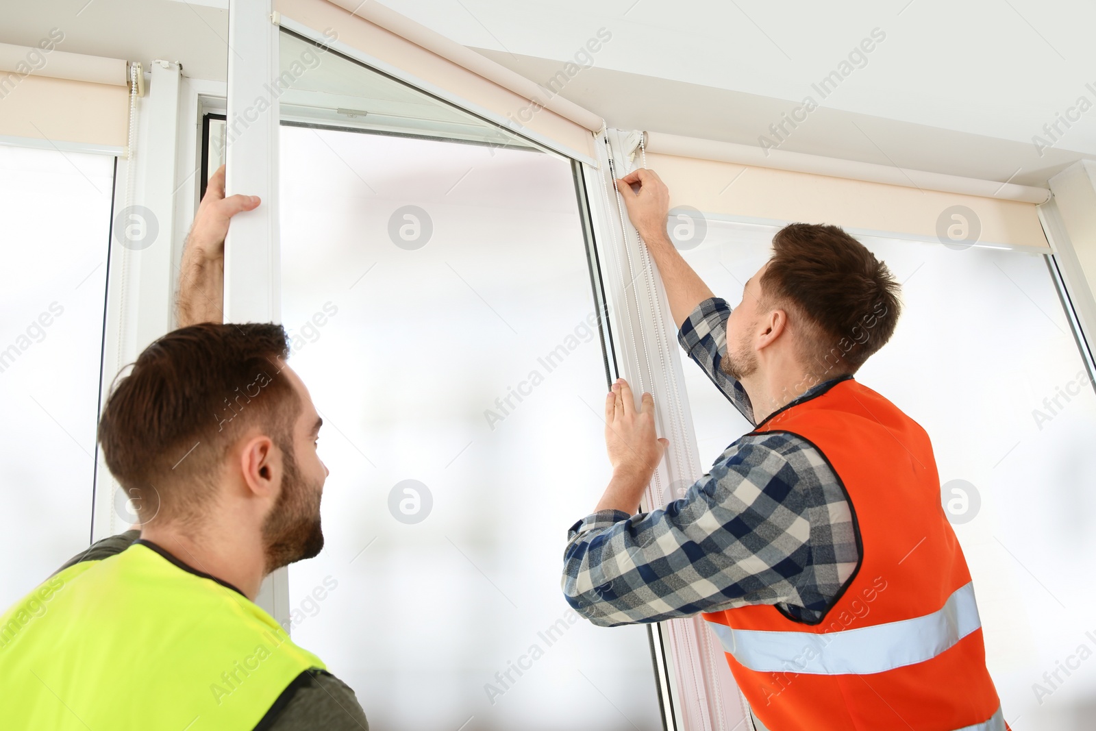 Photo of Construction workers installing plastic window in house