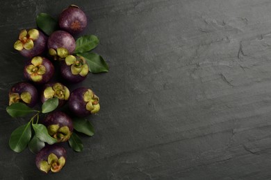 Fresh ripe mangosteen fruits on dark grey table, flat lay. Space for text
