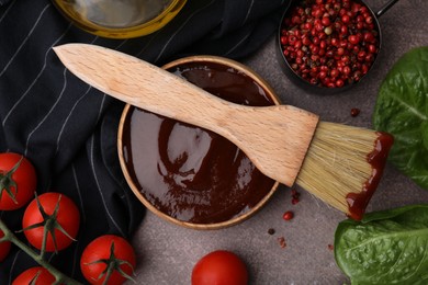 Photo of Flat lay composition with marinade in bowl and basting brush on brown table