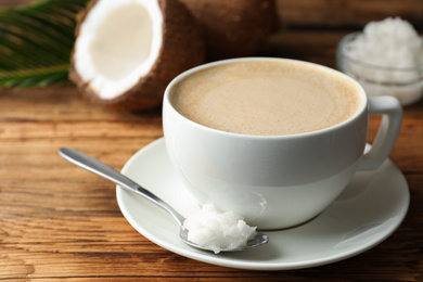 Photo of Delicious coffee with organic coconut oil on wooden table