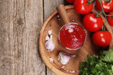 Photo of Delicious ketchup, spices and products on wooden table, top view with space for text. Tomato sauce