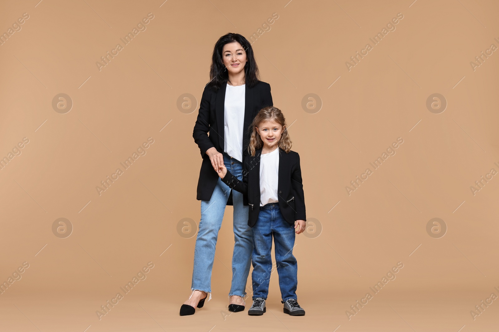 Photo of Beautiful mother with little daughter on beige background