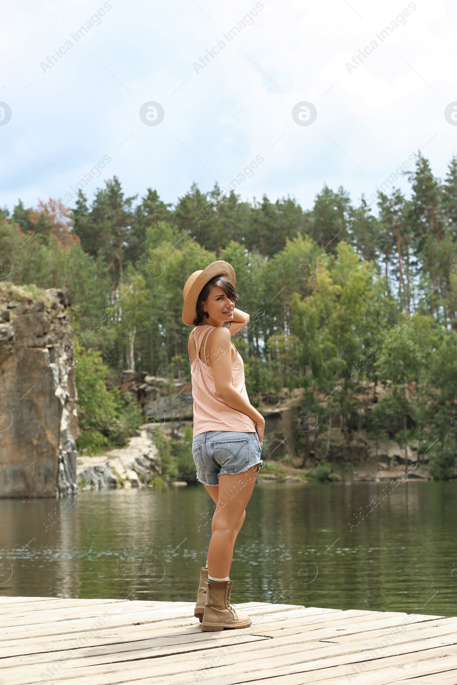 Photo of Young woman on wooden pier near lake. Camping season