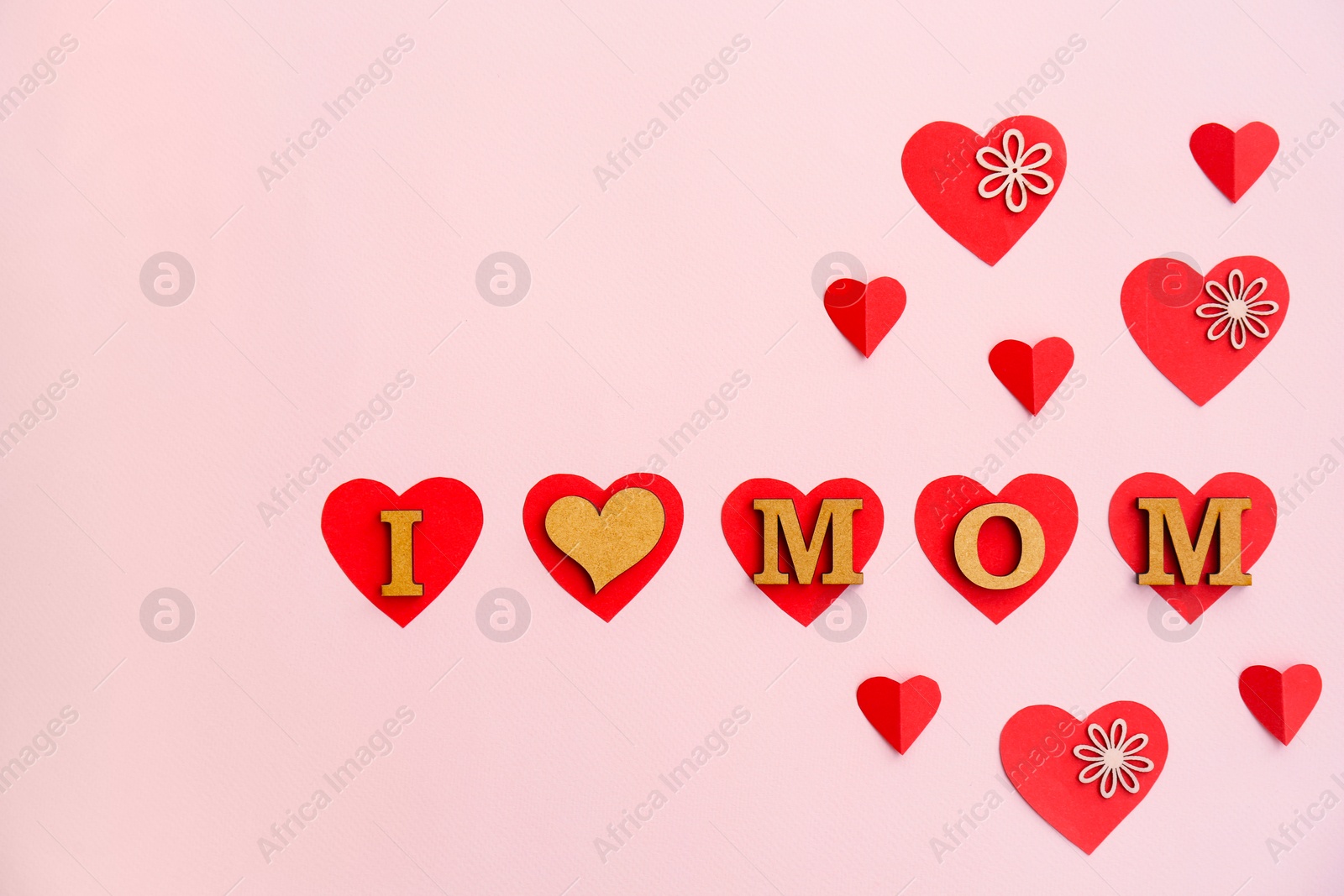 Photo of Phrase "I LOVE MOM" made of letters and paper hearts on color background. Happy Mother's Day