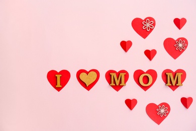 Photo of Phrase "I LOVE MOM" made of letters and paper hearts on color background. Happy Mother's Day